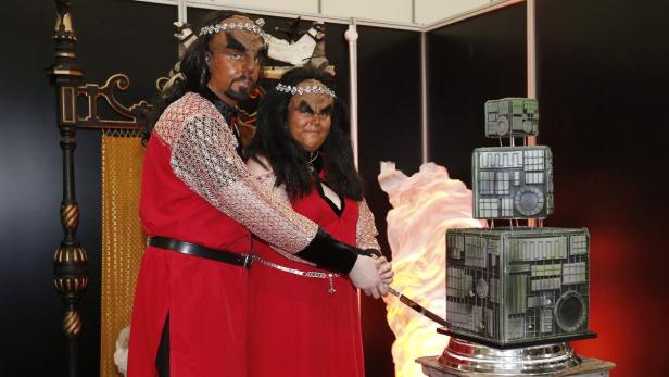 Ein Paar, als Klingonen aus Star Trek verkleidet, schneidet eine Borg-Kuchen an.