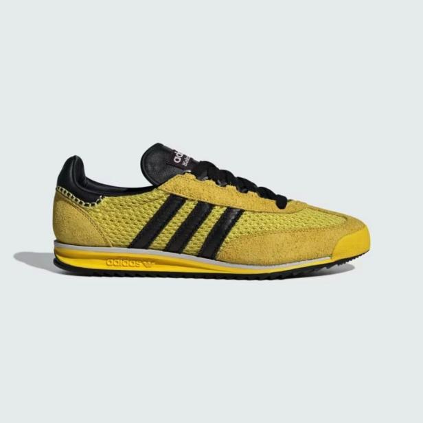 Ein gelber Adidas SL 72 Schuh mit schwarzen Streifen.