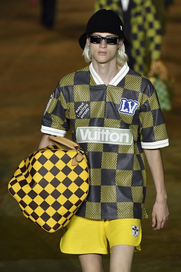 Ein Model mit blonden Haaren präsentiert eine gelb-schwarze Kollektion von Louis Vuitton.