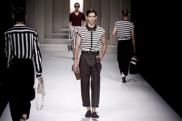 Männliche Models präsentieren gestreifte Oberteile und braune Hosen auf einem Laufsteg.