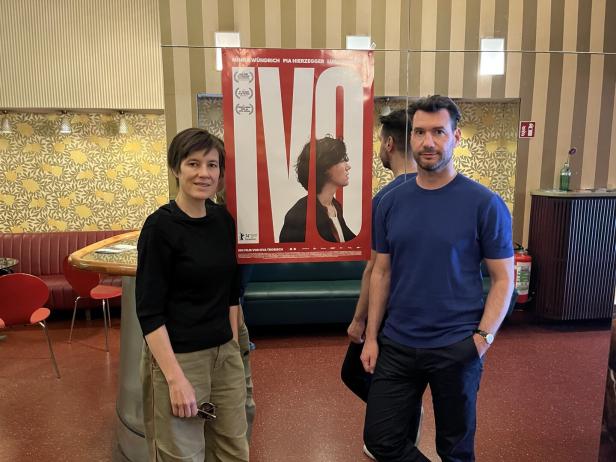 Zwei Personen stehen vor einem Filmplakat mit dem Titel „Ivo“.