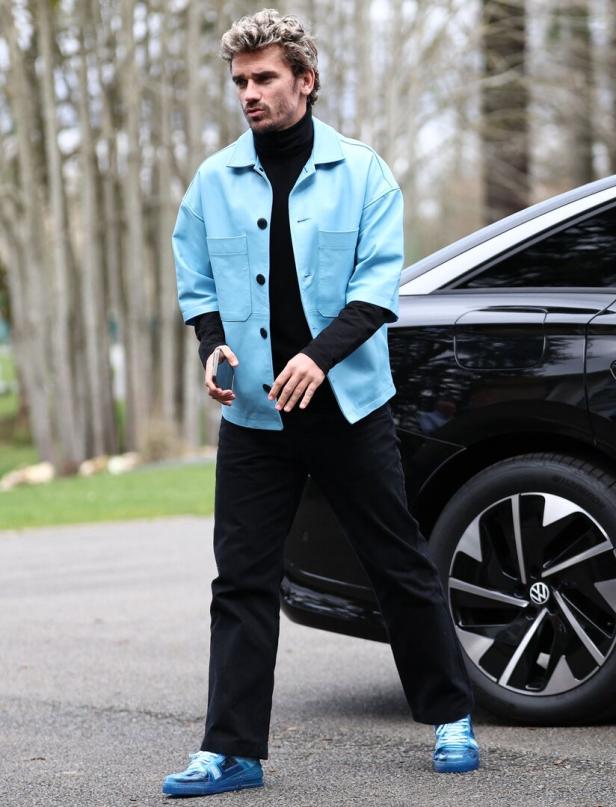 Antoine Griezmann posiert neben einem schwarzen Auto.