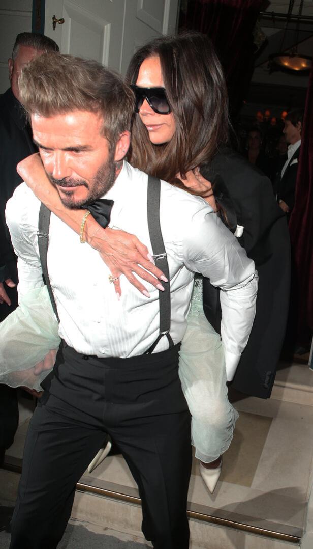 David Beckham trägt Victoria Beckham huckepack.