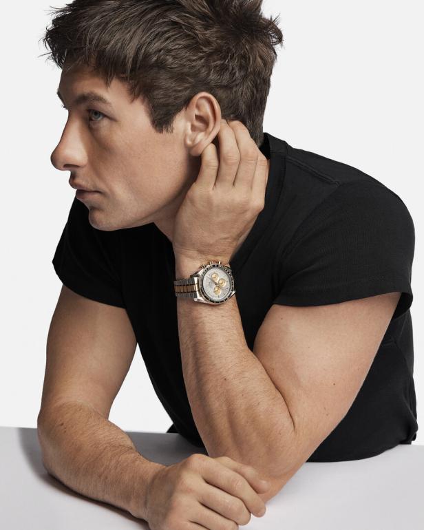 Ein Mann mit schwarzem T-Shirt trägt eine goldfarbene Armbanduhr.