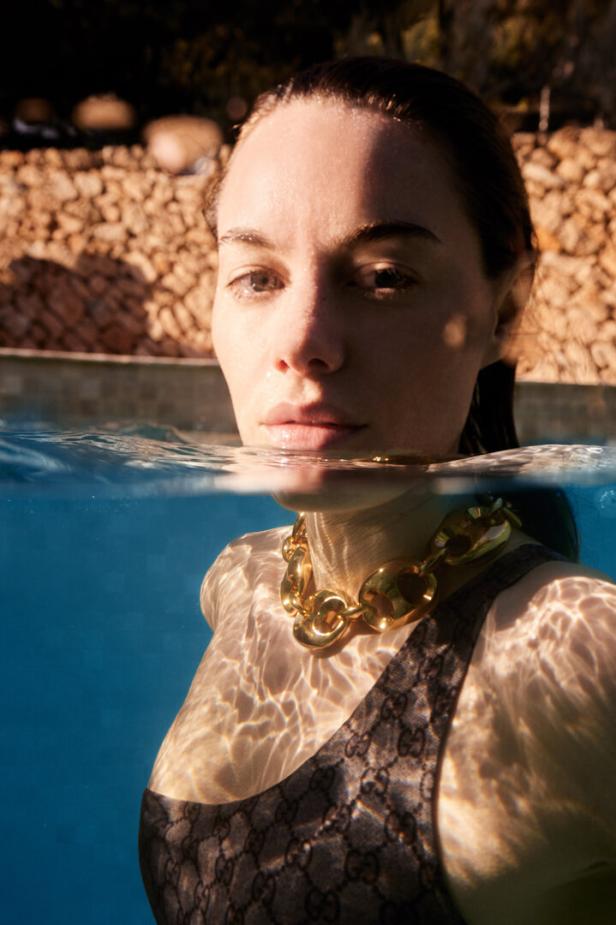 Eine Frau mit einer goldenen Halskette im Wasser.