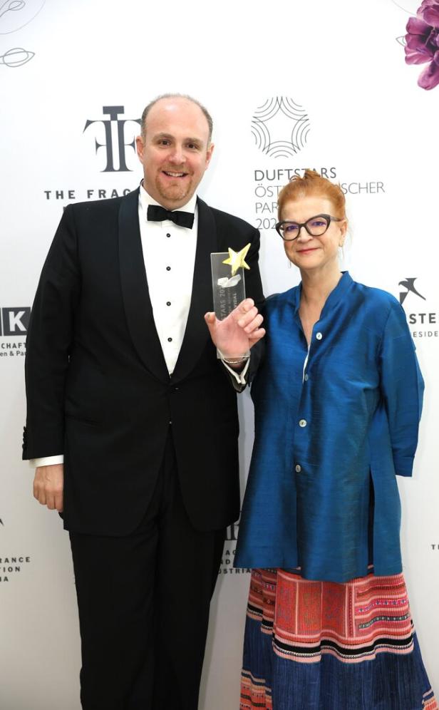 Ein Mann im Smoking und eine Frau mit Brille posieren mit einem „Duftstars“-Award.
