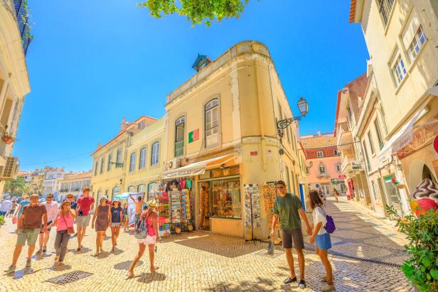 Eine belebte Straße in einer portugiesischen Stadt mit gelben Gebäuden und Touristen.