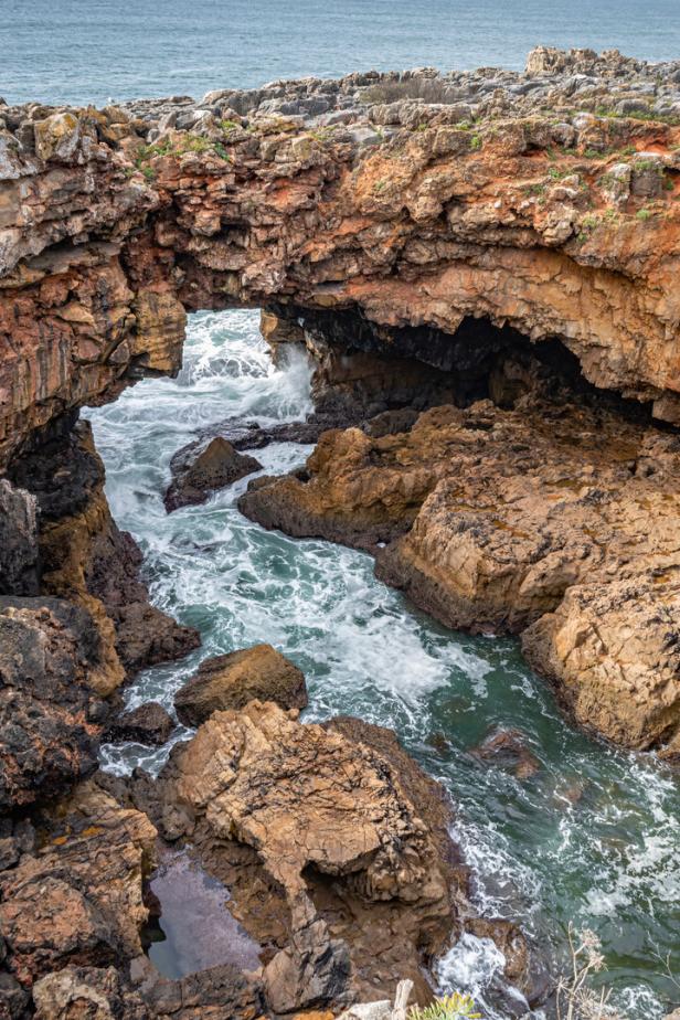 Das Meerwasser strömt durch einen natürlichen Felsbogen an der Küste.