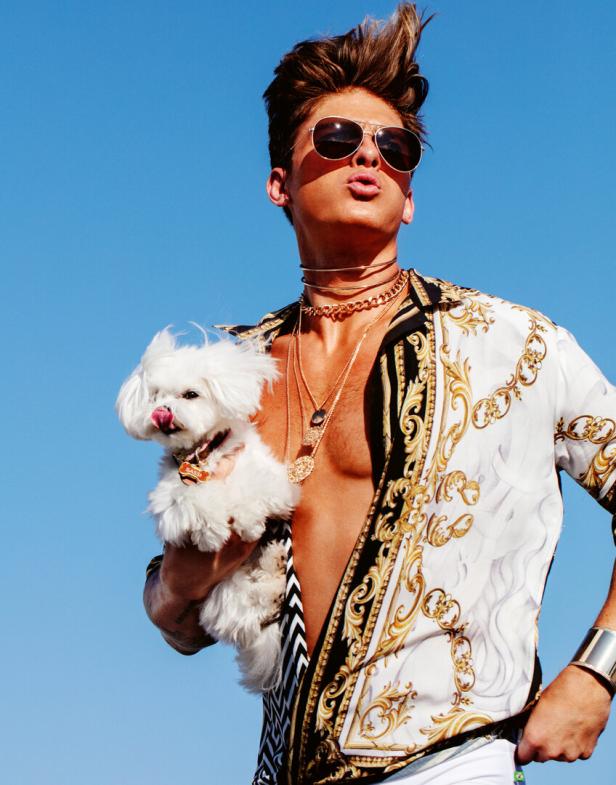 Ein Mann mit Sonnenbrille hält einen kleinen, weißen Hund im Arm.