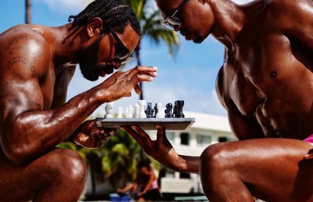 Zwei muskulöse Männer spielen im Freien Schach.