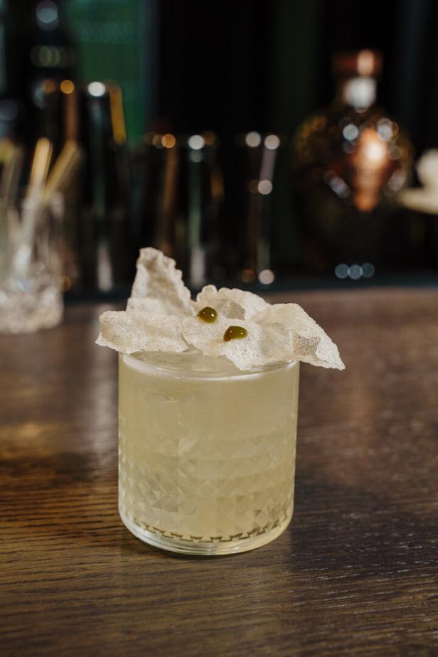 Ein Cocktail mit Eis und essbarer Dekoration auf einer Holzoberfläche.