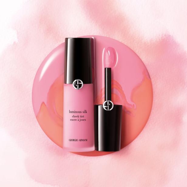 Ein Fläschchen „Luminous Silk Cheek Tint“ von Giorgio Armani mit geöffnetem Applikator auf rosafarbenem Grund.