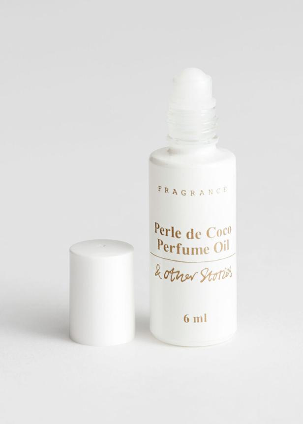 Eine Flasche „Perle de Coco Perfume Oil“ von & Other Stories mit geöffnetem Deckel.