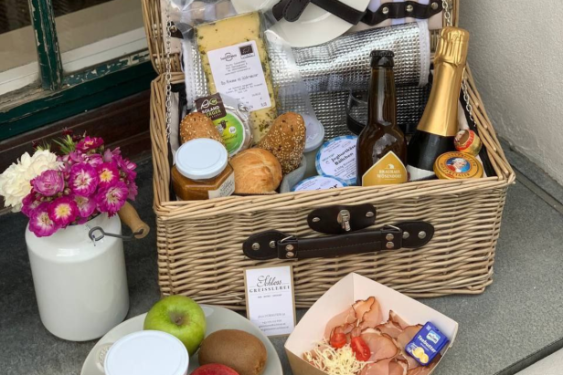 Ein Picknickkorb gefüllt mit Käse, Brot, Getränken und anderen Leckereien.