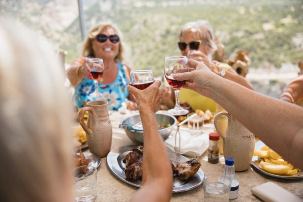 Eine Gruppe älterer Damen stößt mit Weingläsern an um den Urlaub einzuleiten