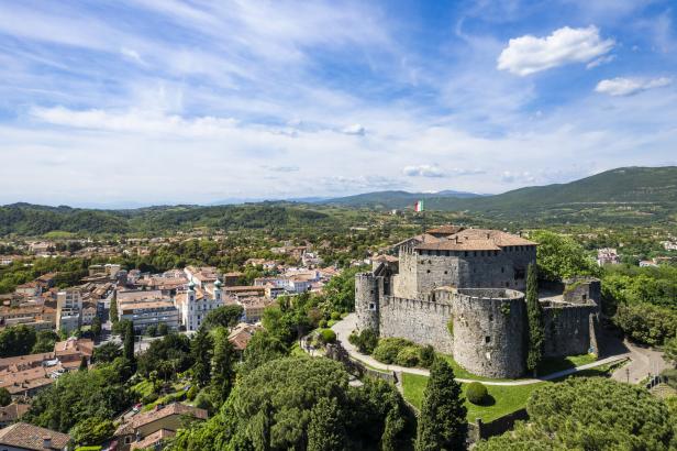 Blick auf eine italienische Stadt mit einer Burg im Vordergrund.