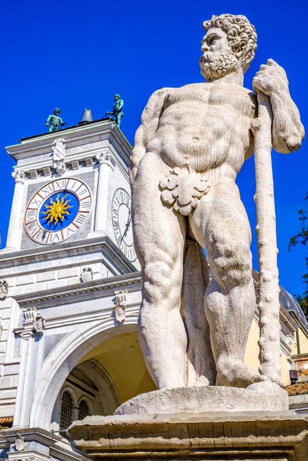 Eine Statue des Herkules vor dem Uhrturm in Udine, Italien.