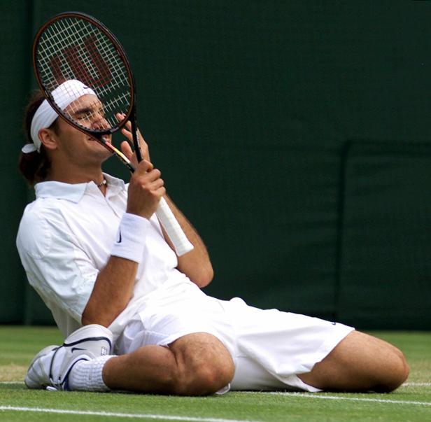 Roger Federer kniet nach einem Tennismatch auf dem Rasen und hält seinen Schläger vors Gesicht.