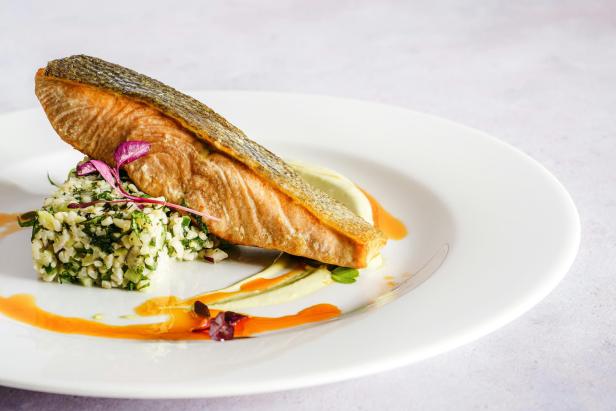 Ein Teller mit gebratenem Lachs, Reis und Soße.