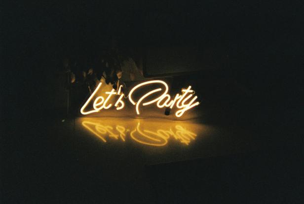 Ein gelbes Neonlicht leuchtet mit der Aufschrift „Let's Party“.