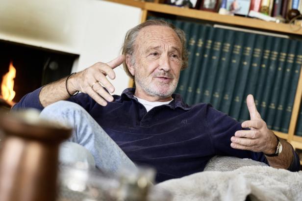 Miguel Herz-Kestranek sitzt vor einer Buchwand und gestikuliert.
