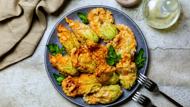 Frittierte Zucchiniblüten auf einem Teller mit Petersilie garniert.