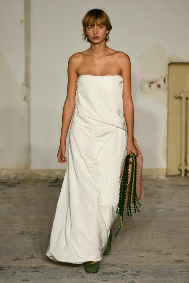 Model posiert im weißen, schulterfreien Kleid.