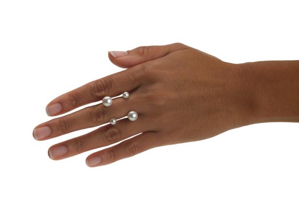 Eine Hand trägt zwei moderne Ringe mit Perlen.