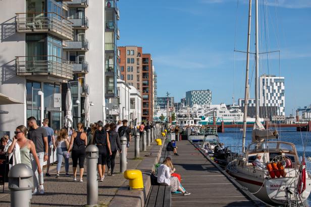 Menschen flanieren an einem sonnigen Tag am Hafen von Kopenhagen entlang.