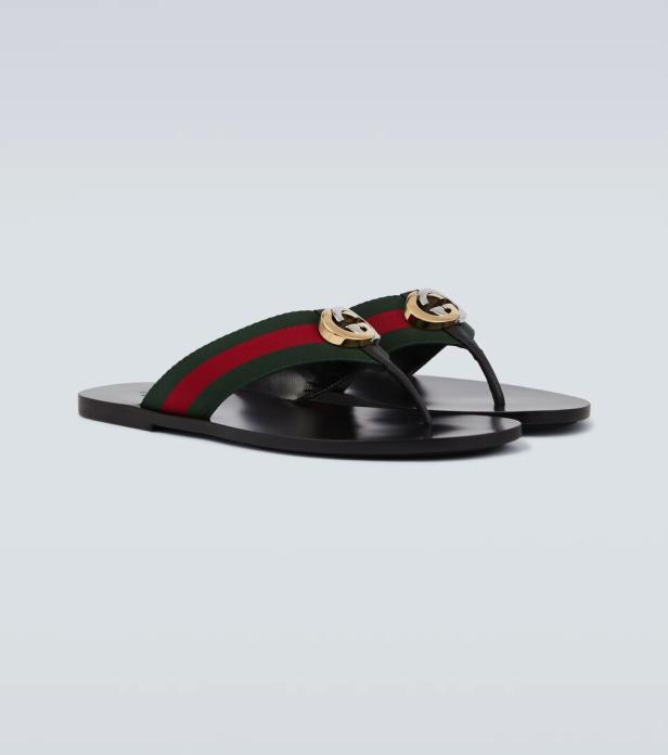 Ein Paar schwarze Gucci-Zehentrenner mit grün-rot-grünem Webstreifen und goldenem Logo.