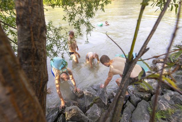 Eine Gruppe von Menschen watet in einem Fluss, einige mit Schwimmhilfen.