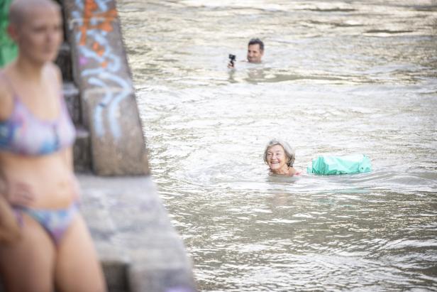 Eine ältere Frau schwimmt mit einer Schwimmhilfe in einem Fluss.
