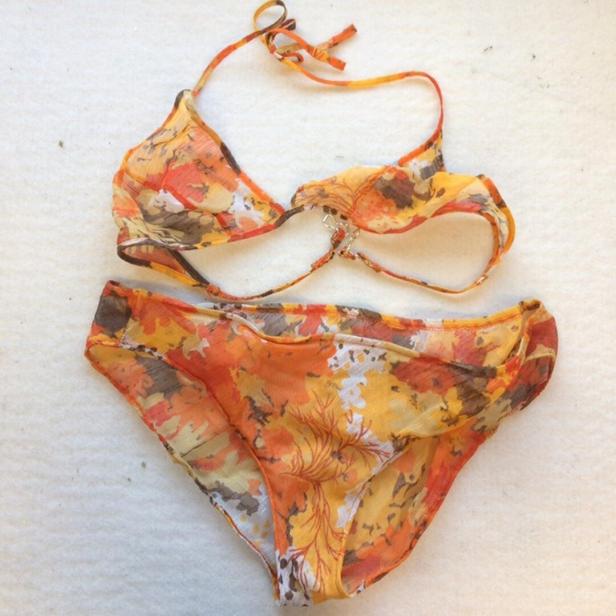 Ein orangefarbener Bikini mit floralem Muster liegt auf einem weißen Hintergrund.