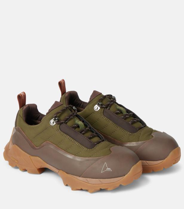 Ein Paar olivgrüne und braune Wanderschuhe vor einem neutralen Hintergrund.