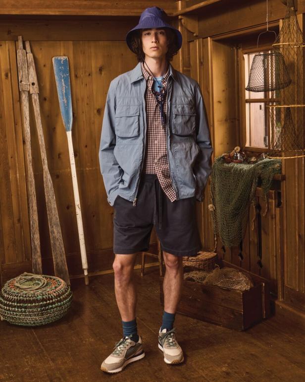 Ein Mann in Shorts, Hemd und Jacke steht in einem Raum mit nautischem Dekor.