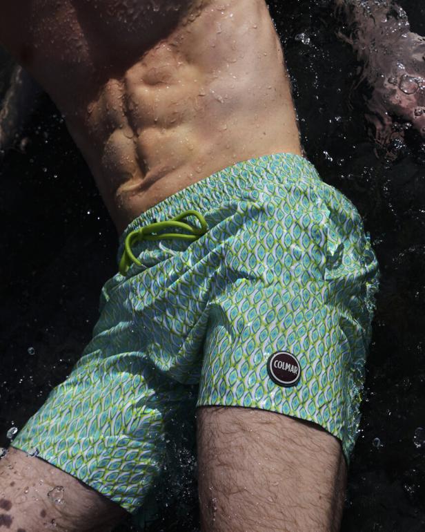 Ein Mann mit Badehose der Marke Colmar steht im Wasser.