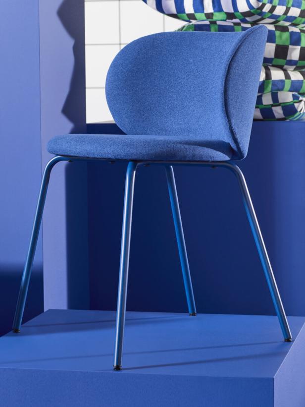 Ein blauer Stuhl mit Metallbeinen steht auf einer blauen Plattform.