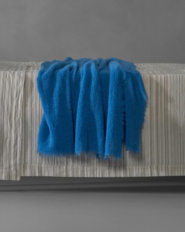Eine blaue Decke liegt auf einem Tisch mit gestreifter Tischdecke.