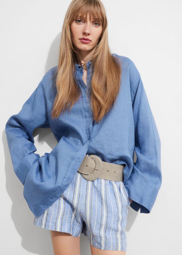 Eine Frau trägt ein blaues Hemd und gestreifte Shorts mit einem breiten Gürtel.