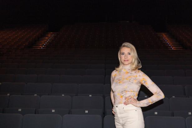 Eine Frau steht in einem leeren Theatersaal.
