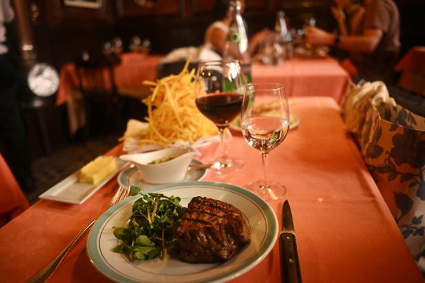 Ein gedeckter Tisch mit Steak, Pommes und Getränken in einem Restaurant.