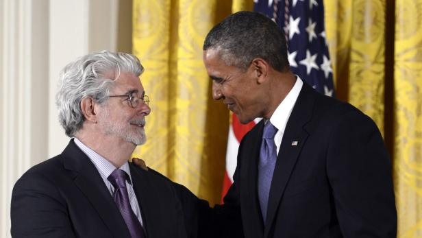 George Lucas und Barack Obama stehen zusammen vor einer US-Flagge.