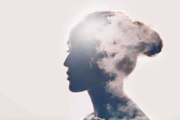 Das Profil einer Frau, deren Kopf teilweise von Wolken bedeckt ist.