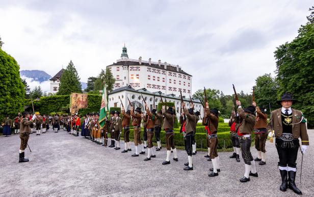 Vor Schloss Ambras feuern Schützen in Tracht mit Gewehren in die Luft.
