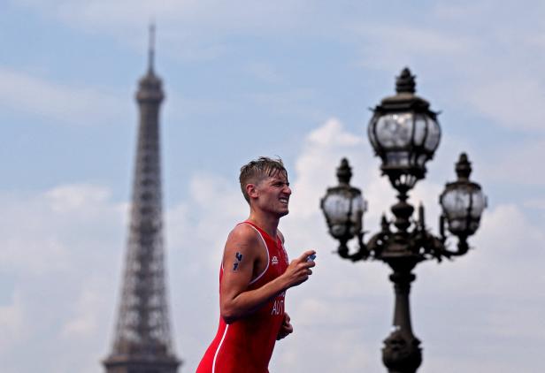 Ein Triathlet läuft in Paris mit dem Eiffelturm im Hintergrund.