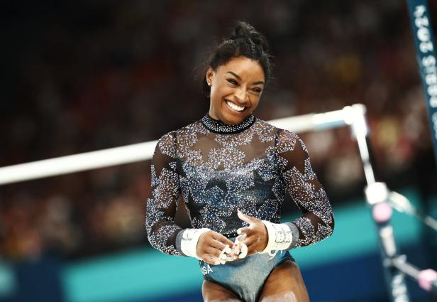 Simone Biles lächelt bei einem Gymnastikwettkampf.