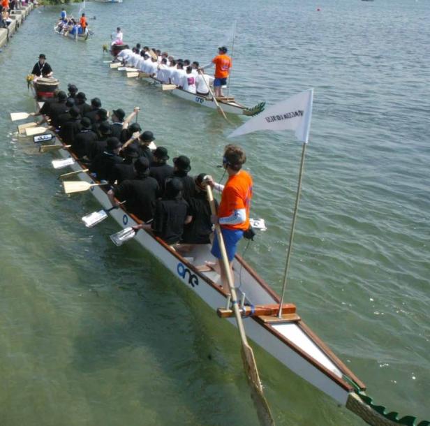 Zwei Drachenboote mit Paddlern nehmen an einem Rennen auf dem Wasser teil.