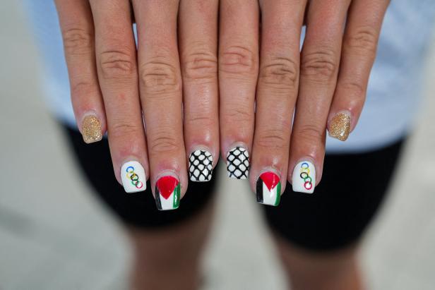 Nahaufnahme von Händen mit Nagelkunst, darunter die Farben der palästinensischen Flagge und die olympischen Ringe.