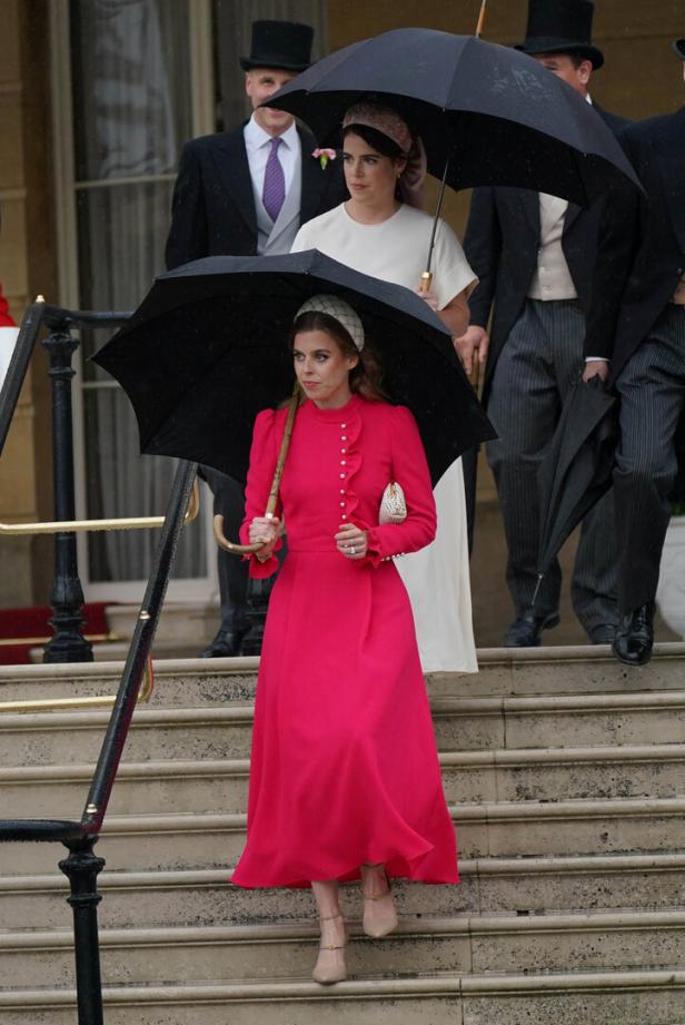 Prinzessin Beatrice geht mit einem pinkfarbenen Kleid und einem Regenschirm eine Treppe hinunter.