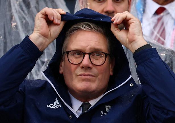 Keir Starmer zieht bei Regenwetter die Kapuze seiner Jacke über den Kopf.